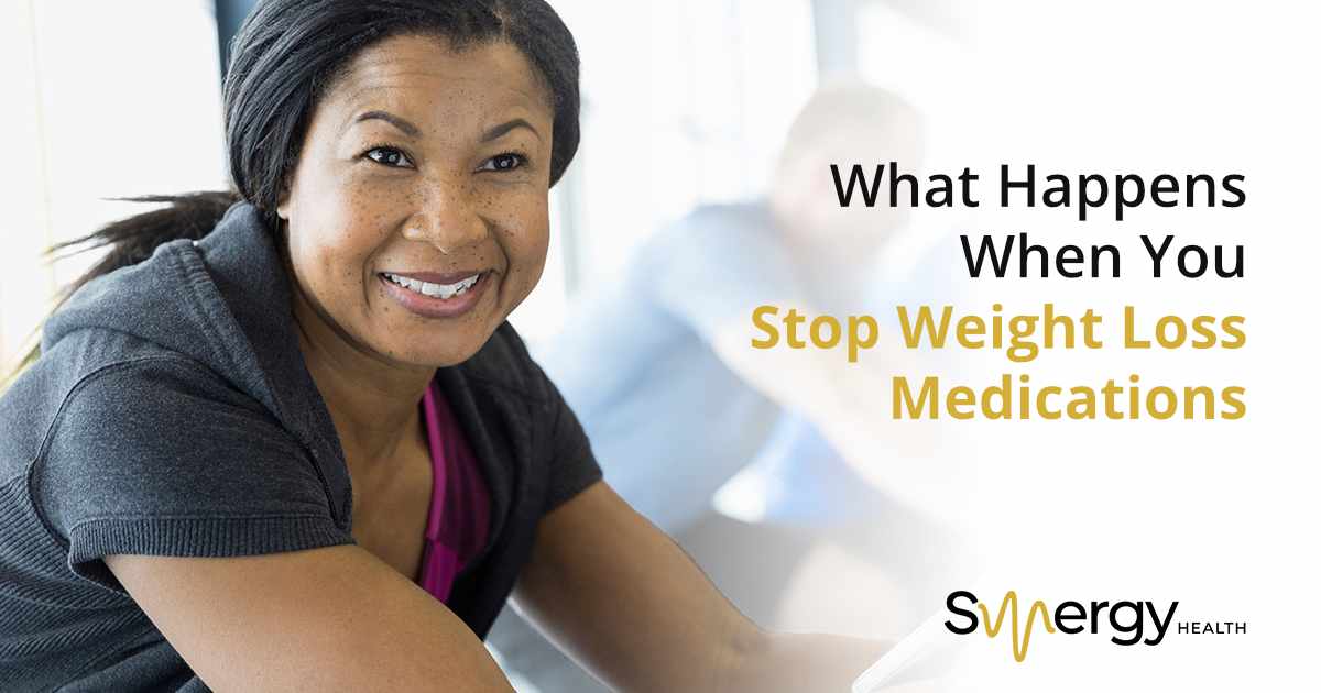 Joyful indoor cycling session at a gym, featuring Synergy Health and highlighting its comprehensive wellness and fitness services available.