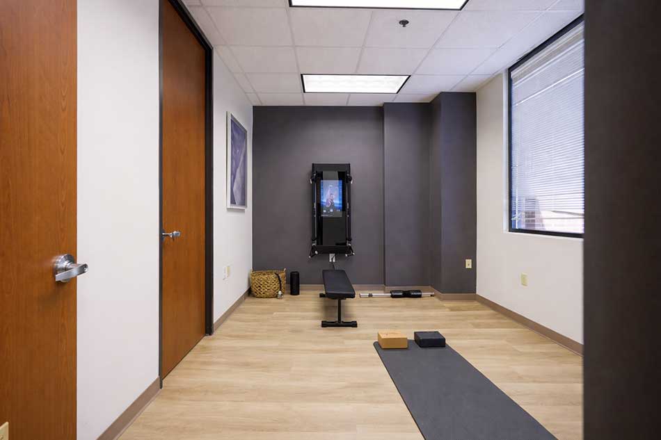 Synergy Health fitness room with exercise bench, mat, and digital training equipment.