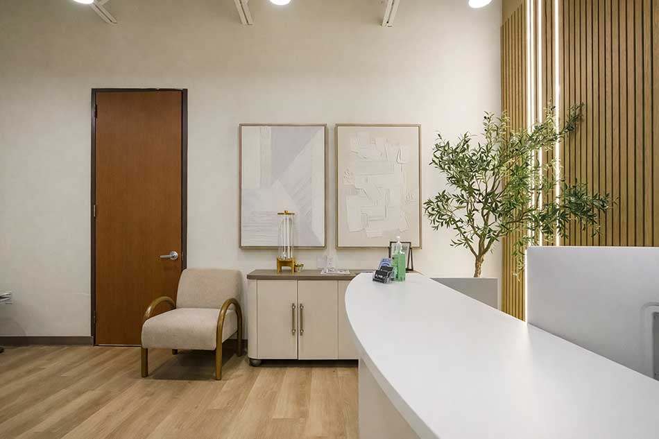 Synergy Health front desk and reception corner with seating and wood accent wall.