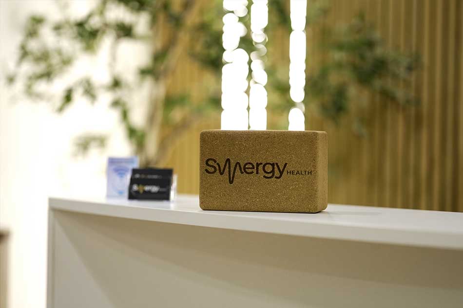 Synergy Health logo display on the reception desk in the office lobby.