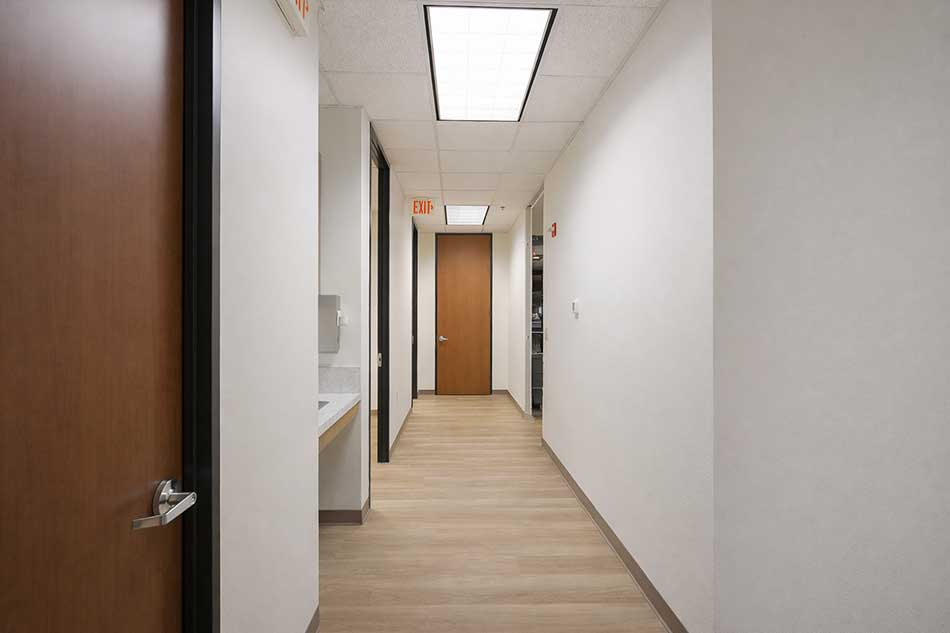 Synergy Health medical office hallway with wood flooring and exam room access.
